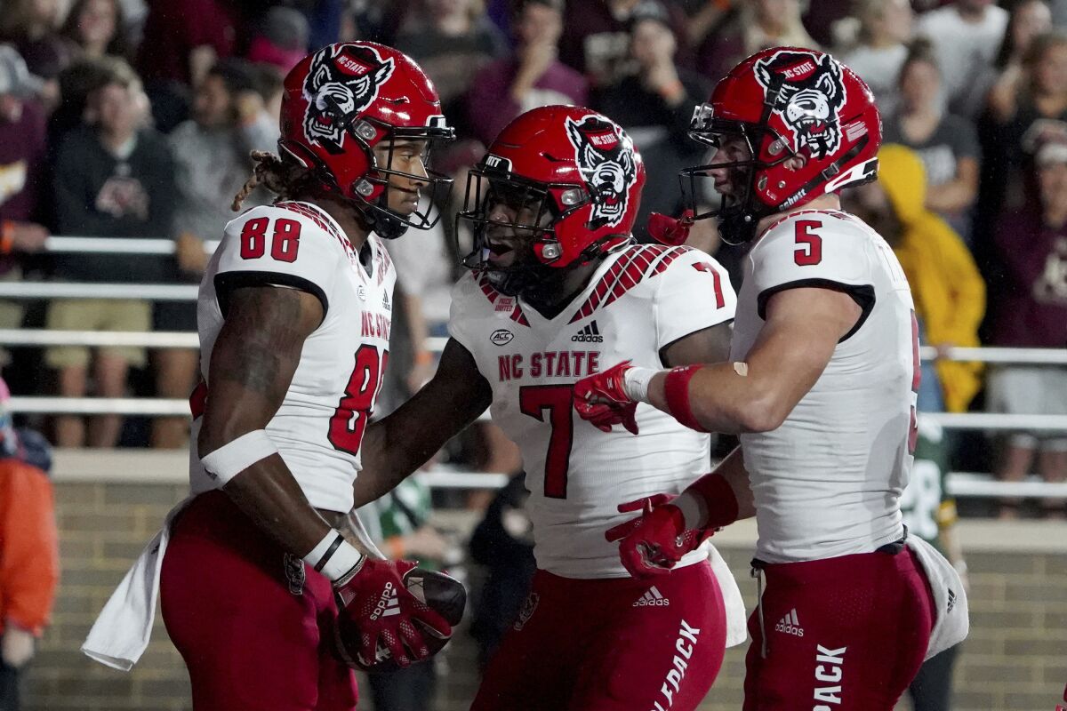 North Carolina State wide receiver Devin Carter (88) is congratulated by teammates Zonovan Knight (7) and Thayer Thomas (5) after scoring a touchdown during the first half of an NCAA college football game against Boston College, Saturday, Oct. 16, 2021, in Boston. (AP Photo/Mary Schwalm)
