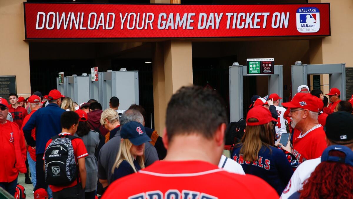 A sign telling game attendees to download their game day ticket is displayed above the entrance to Angel Stadium on opening day on Thursday.