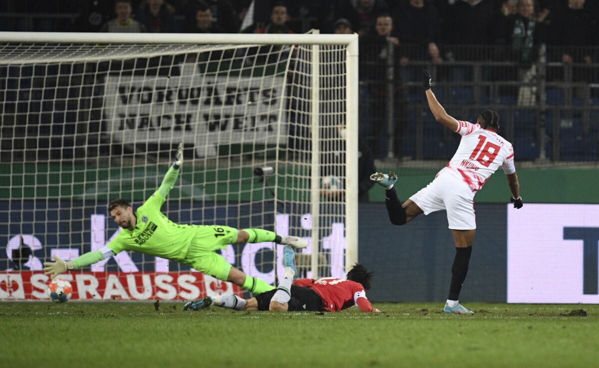 Leipzig's Christopher Nkunku, right, scores his side's first goal of the game past Hannover goalkeeper Ron-Robert Zieler during the German Cup quarter final soccer match between Hannover 96 and RB Leipzig at the HDI Arena in Hanover, Germany, Wednesday, March 2, 2022. (Daniel Reinhardt/dpa via AP)