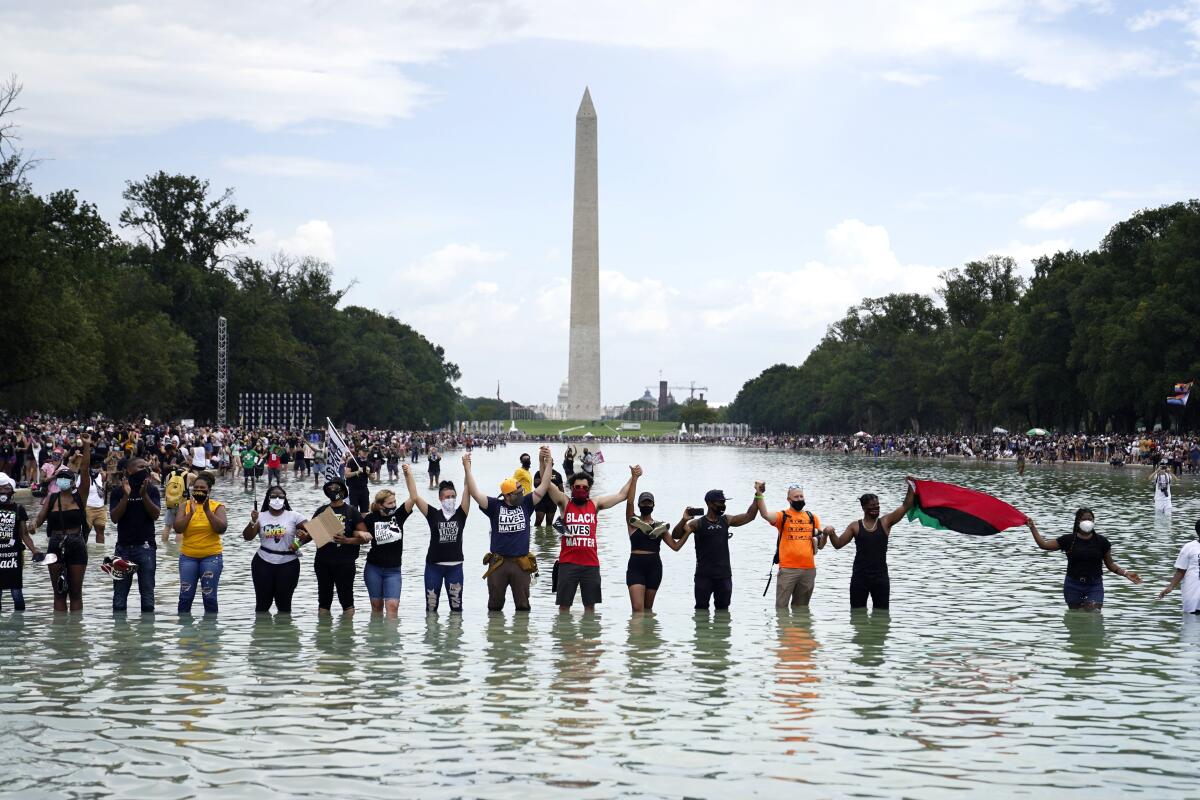 People joined hands in the Reflecting Pool in the shadow of the Washington Monument last August