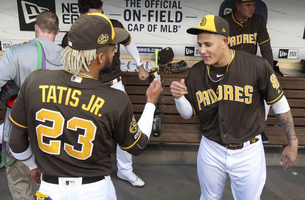 The Padres' Fernando Tatis Jr., left, and Manny Machado greet each in the dugout before the start of the Padres game against the Reds.