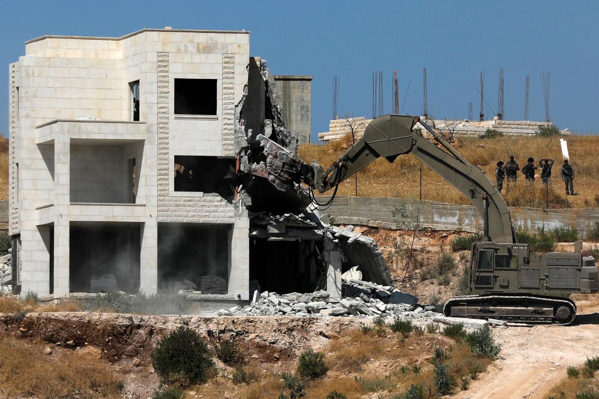 Israeli security forces tear down one of the Palestinian buildings still under construction in the West Bank village of Dar Salah on Monday.