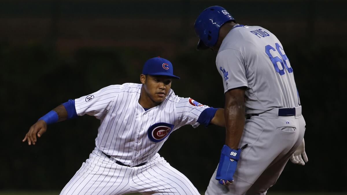 Chicago Cubs second baseman Addison Russell, left, tags out Dodgers baserunner Yasiel Puig during the third inning of the Dodgers' 4-2 loss at Wrigley Field on Monday.