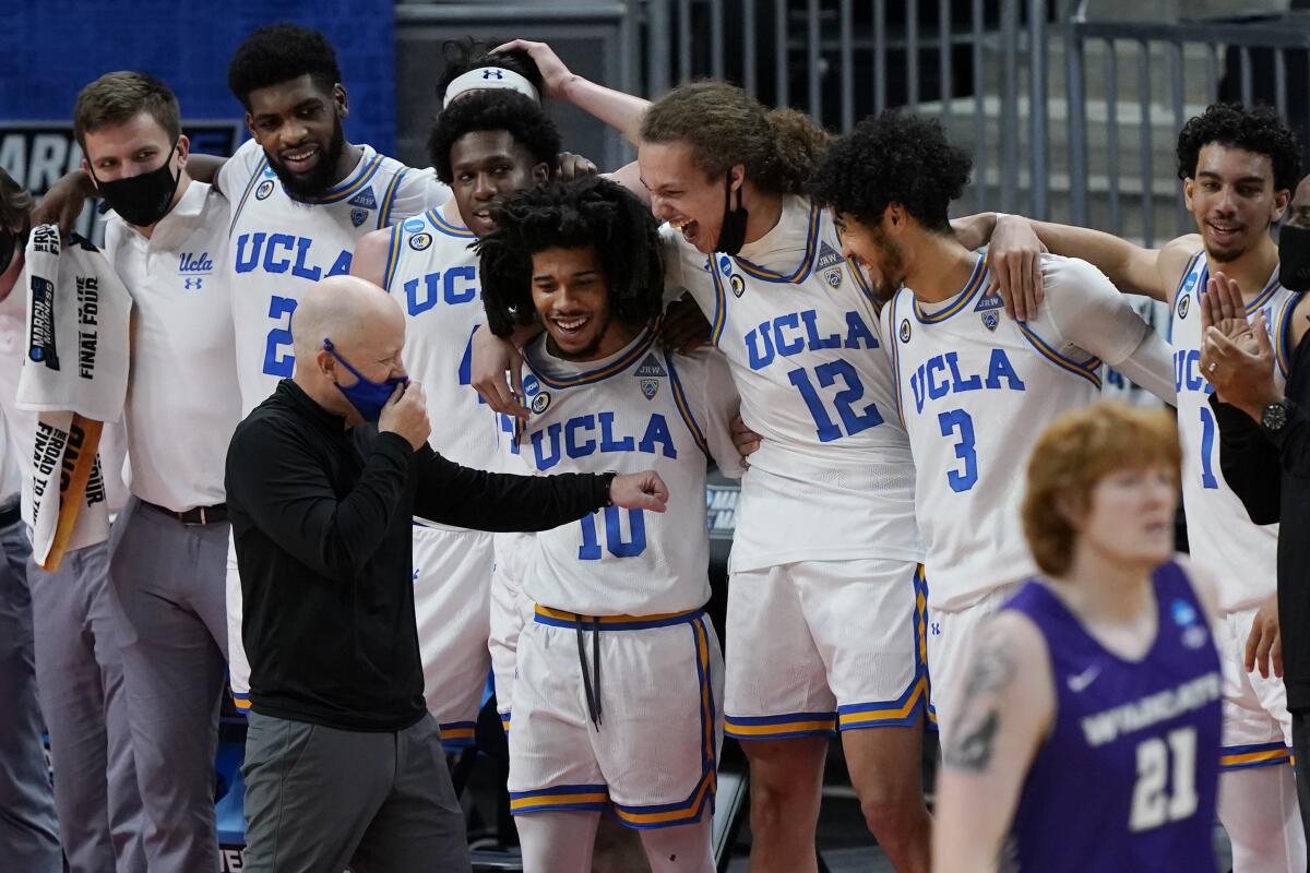 UCLA coach Mick Cronin celebrates with players during an NCAA tournament win.