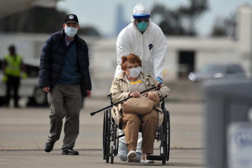 Medical personnel help load passengers from the Grand Princess cruise ship onto airplanes at Oakland International Airport in Oakland, California on March 10, 2020. - The first passengers were taken ashore from a coronavirus-hit cruise ship that docked at California's port of Oakland on March 9, 2020, with the infected "being dealt with in proper isolation," said US Vice President Mike Pence. The Grand Princess arrived in the San Francisco Bay after days stranded at sea with 21 confirmed coronavirus infections among more than 3,500 passengers and crew. (Photo by Josh Edelson / AFP) (Photo by JOSH EDELSON/AFP via Getty Images)