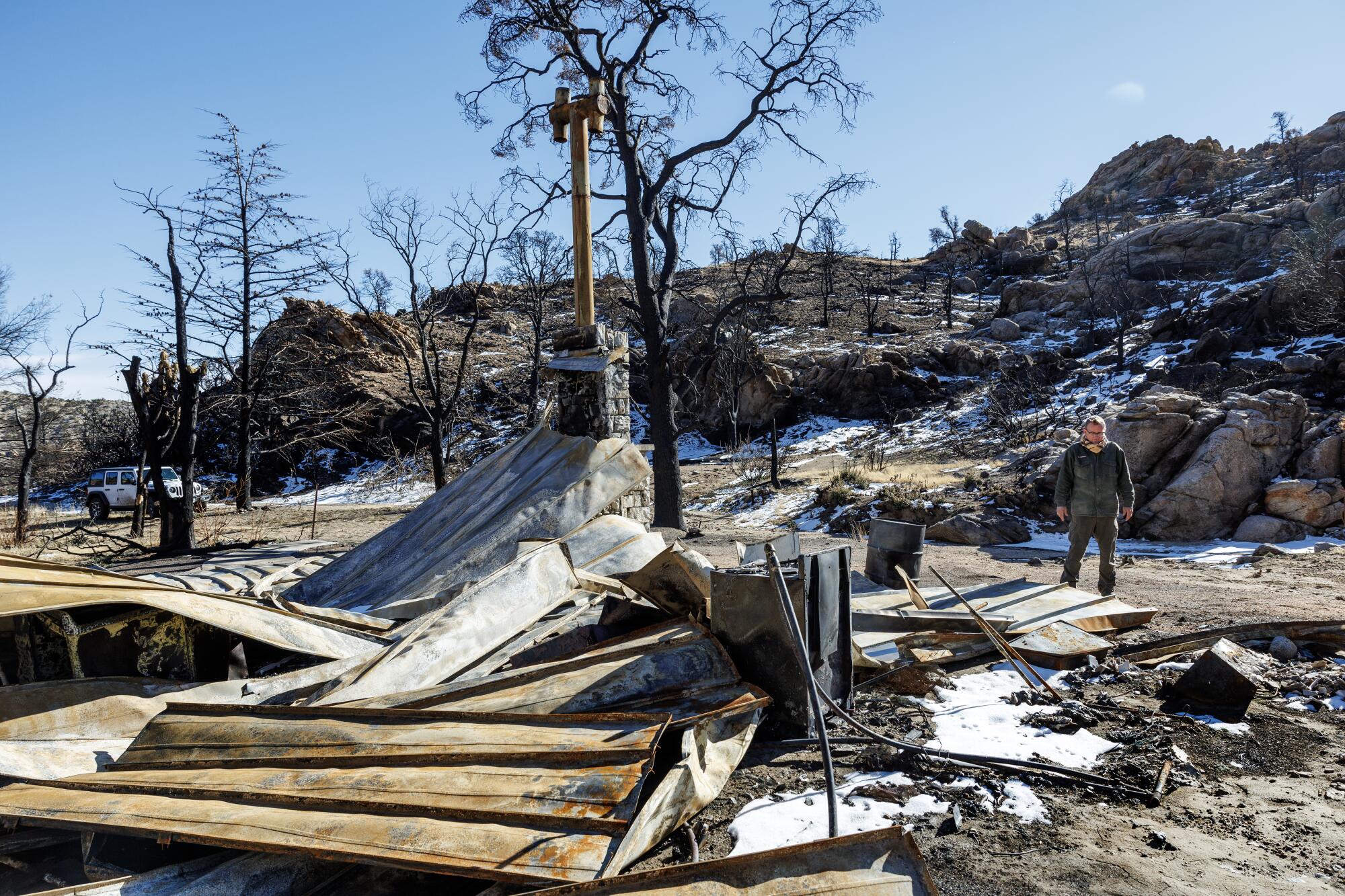 A man surveys the remains of a burned cabin.