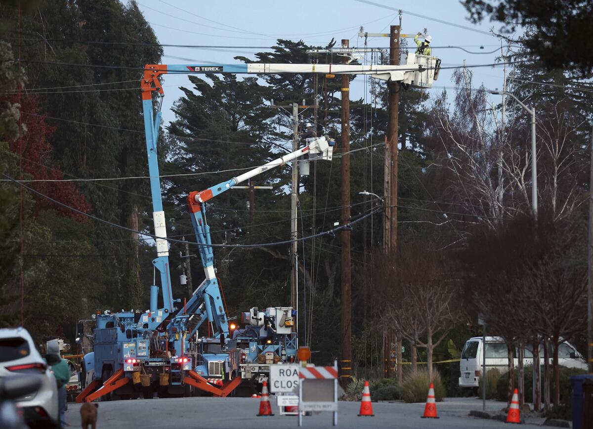 PG&E workers replace equipment damaged by high winds.