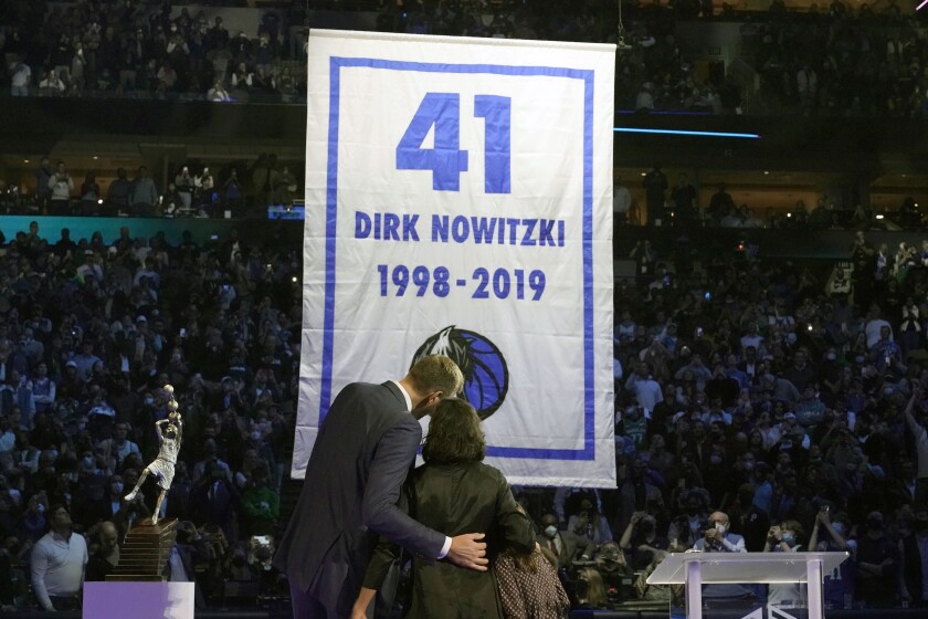 Former Dallas Mavericks Dirk Nowitzki, left, and his wife Jessica Olsson watch a banner being raised during a number retirement ceremony for Nowitzki after an NBA basketball game between the Golden State Warriors and Dallas Mavericks in Dallas, Wednesday, Jan. 5, 2022. (AP Photo/LM Otero)