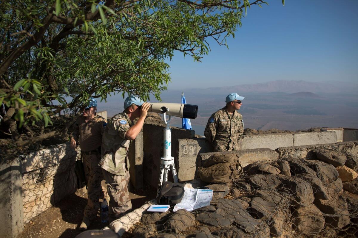 Members of a United Nations force watch the Syrian side of the Golan Heights at Mount Bental.