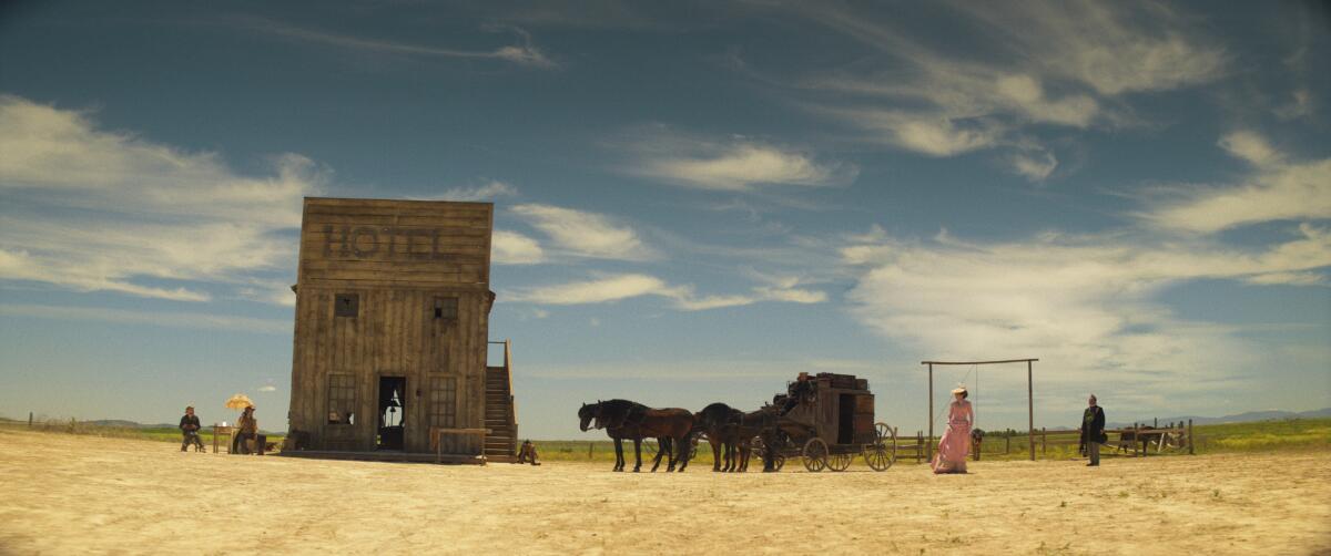 A western landscape dotted with people under a blue sky.