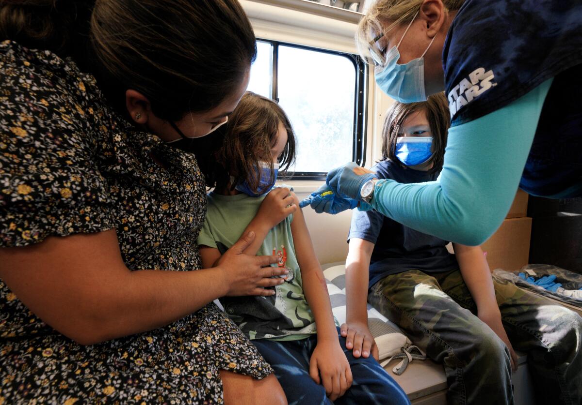 Julie Brown, with UC San Diego Health, vaccinated Beau Tafoya, 5, as his brother Luca,11 watched in the medical van. 
