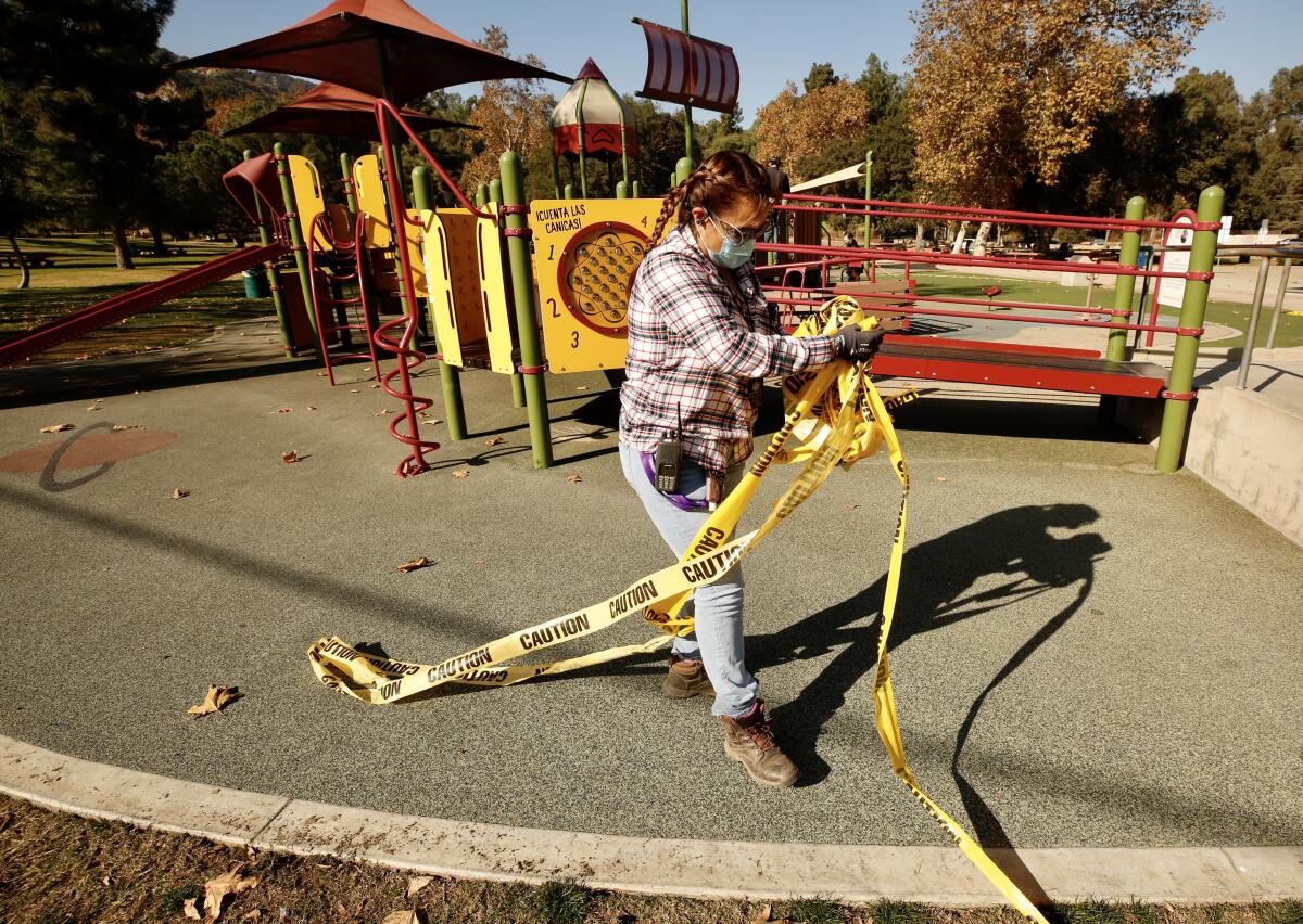 A gardener gathers yellow tape that enclosed a Griffith Park playground during COVID