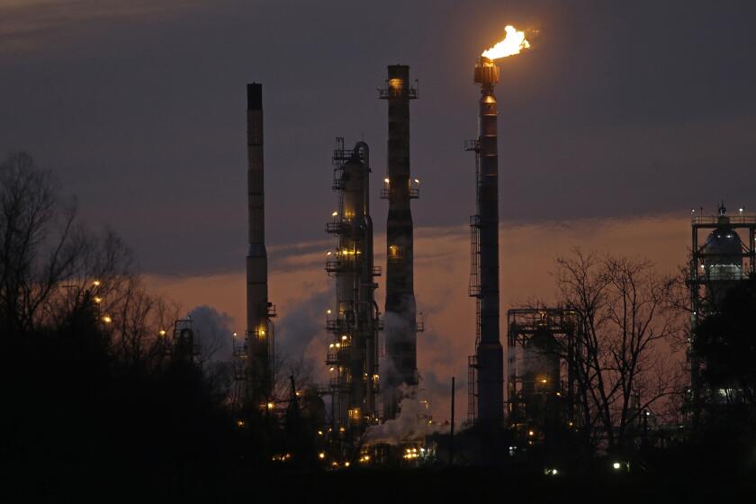 FILE - In this Feb. 13, 2015 file photo, stacks and burn-off from the ExxonMobil refinery are seen at dusk in St. Bernard Parish, La. New York City officials say they will begin the process of dumping about $5 billion in pension fund investments in fossil fuel companies, including Exxon Mobil, because of environmental concerns. (AP Photo/Gerald Herbert, File)
