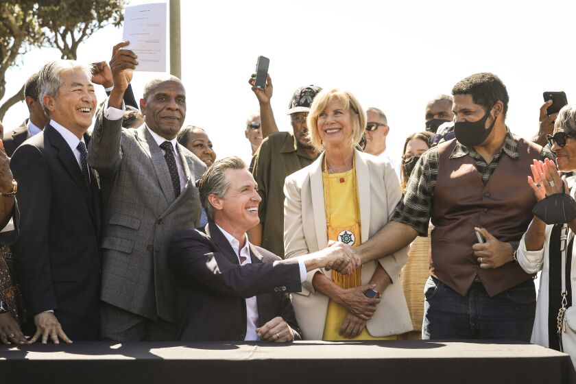 Manhattan Beach, CA - September 30: California Assemblyman Al Muratsuchi, California Senator Steven Bradford, Gov. Gavin Newsom, Los Angeles County Supervisor Janice Hahn and Anthony Bruce, great-great grandson of Charles and Willa Bruce, from left at table, during Newsom's signing of SB 796, authored by Ca. state Senator Bradford, authorizing the return of ocean-front land to the Bruce family, during a press conference held at Bruce's Beach in Manhattan Beach, CA, Thursday, Sept. 30, 2021. Some of the land making up Bruce's Beach was purchased by African American couple Willa and Charles Bruce, in 1912, establishing a resort that was open to African Americans. But by the 1920s, racial tensions grew in the beach community and the city condemned the properties. The park was renamed multiple times over the next 80 years and in 2007, was re-named for the Bruce family, responsible for trying to bring change and equality to the city. (Jay L. Clendenin / Los Angeles Times)
