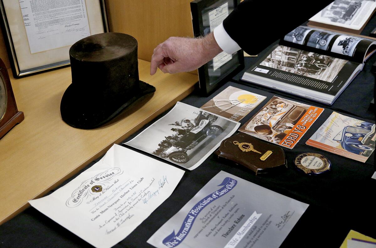 David Robins shows vintage advertising memorabilia and a top hat his grandfather wore, part of a 100th anniversary display.