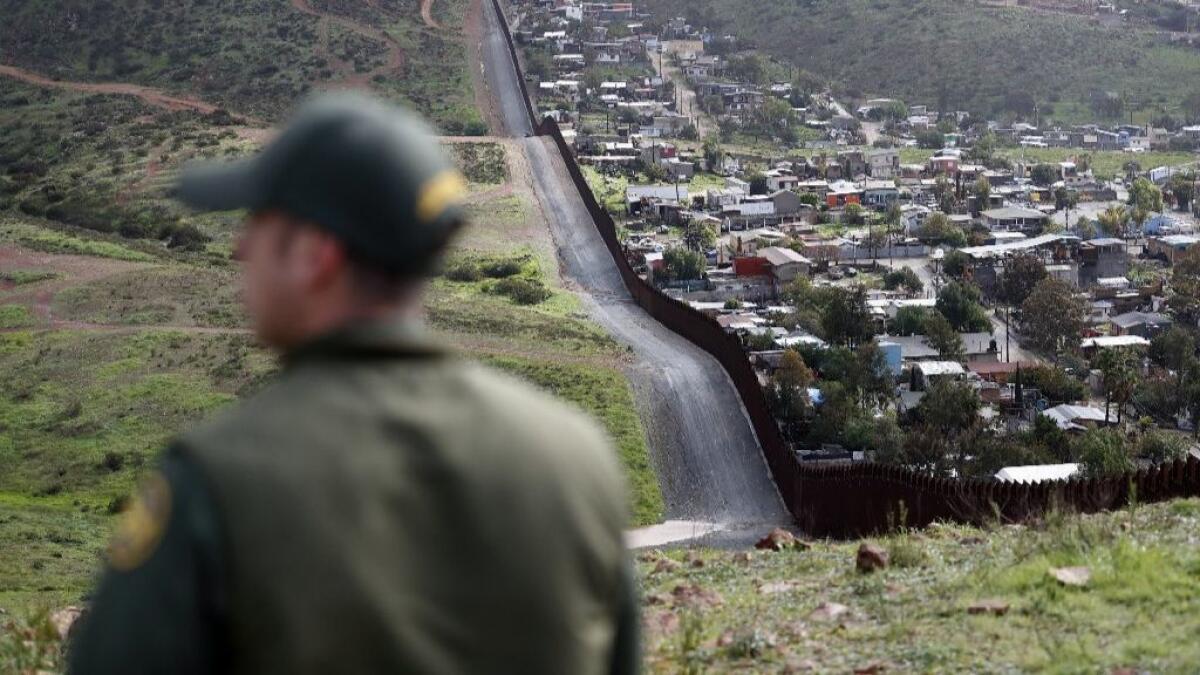 A Border Patrol agent looks on near a border wall that separates the cities of Tijuana, Mexico, and San Diego on Feb. 5.