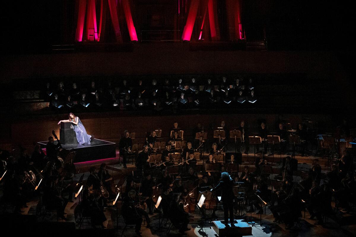 Una mujer brilla en una plataforma colocada entre los miembros de la Orquesta Filarmónica de Los Ángeles.