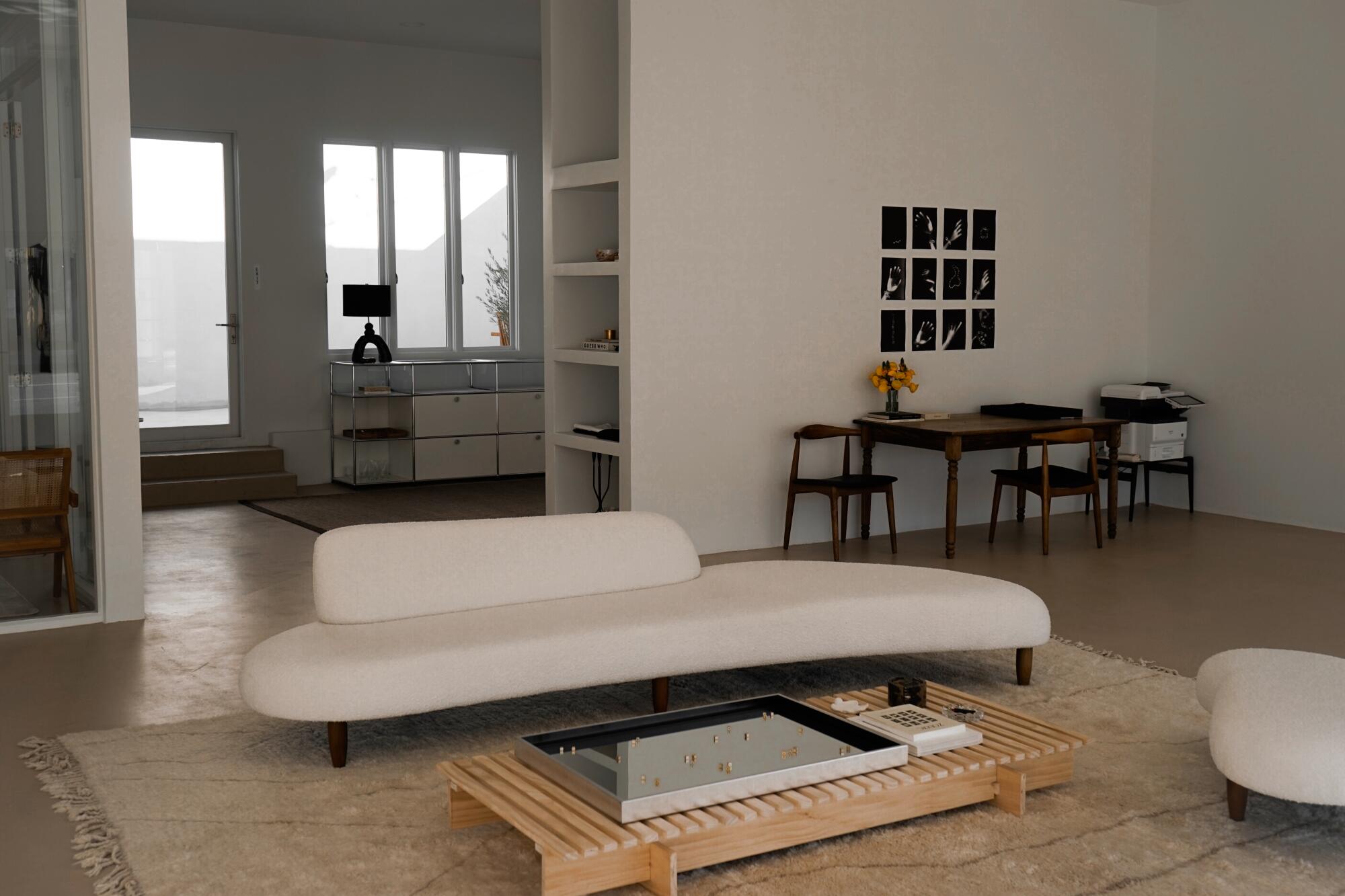 A white biomorphic couch and low wooden table inside Tase Gallery
