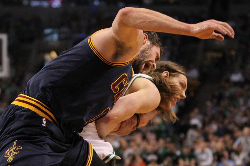 Cavaliers forward Kevin Love, left, yells with pain as he is dragged by the arm by Celtics center Kelly Olynyk.