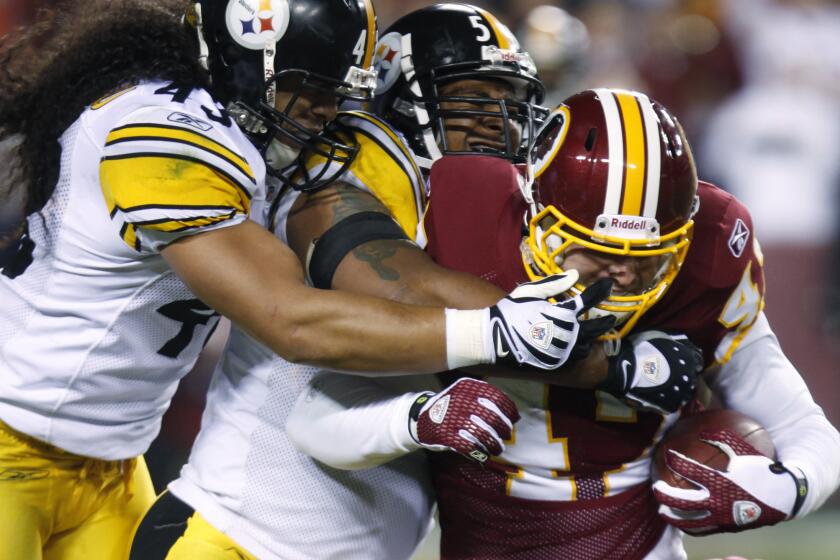 Washington Redskins tight end Chris Cooley, right, is tackled by Pittsburgh Steelers safety Troy Polamalu, left, and linebacker LaMarr Woodley during the fourth quarter of an NFL game on Nov. 3, 2008.