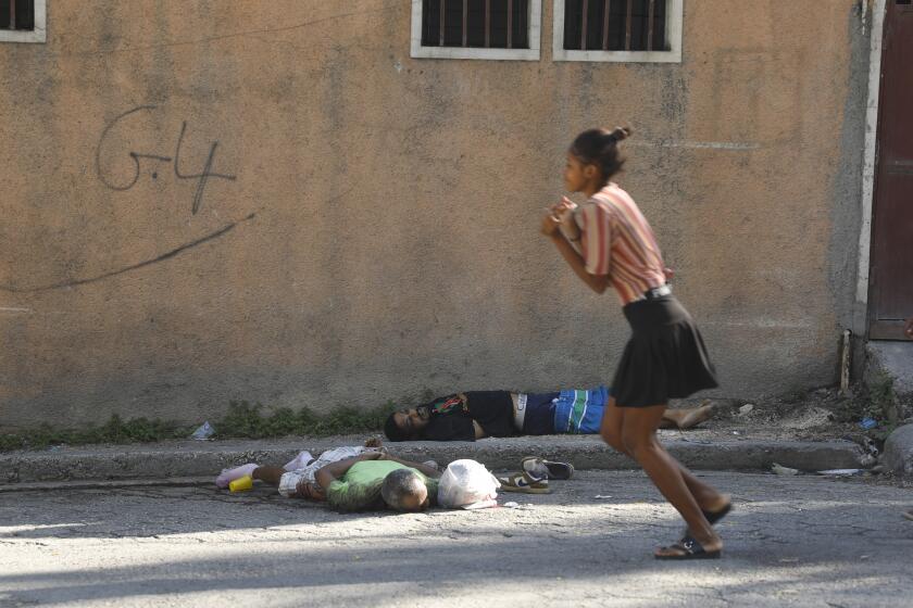 Una mujer pasa junto a los cuerpos de dos hombres asesinados por agresores desconocidos en Puerto Príncipe, Haití, el domingo 3 de marzo de 2024. Cientos de presos huyeron de la principal prisión de Haití después de que pandilleros armados asaltaran el complejo durante la noche. (AP Foto/Odelyn Joseph)