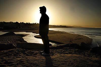 The sunrise casts a glow over Dana Point resident Neal Mofhitz on Doheny State Beach, where a 25,000-gallon raw sewage spill on Friday has kept the shoreline closed.