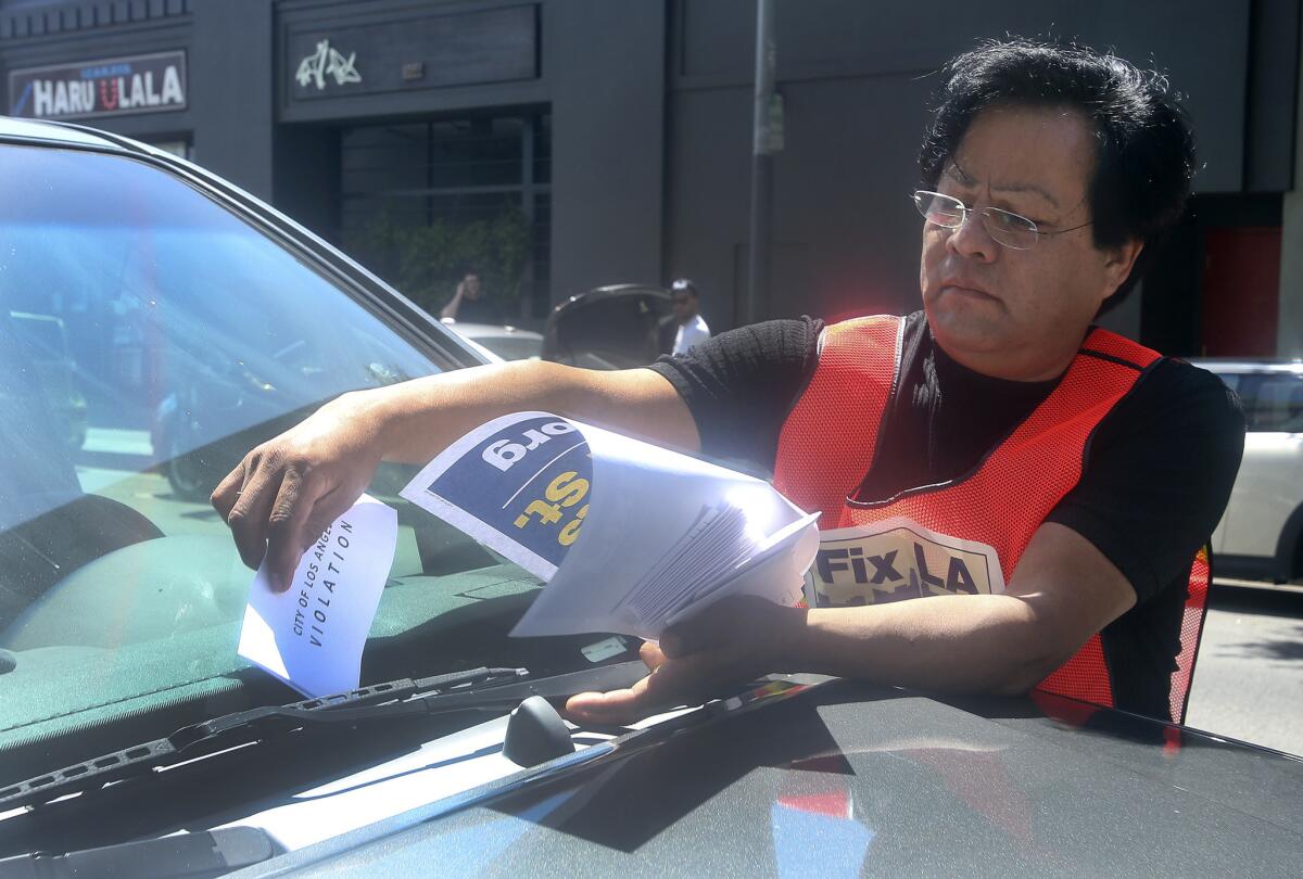 Jose Morales, a member of SEIU 721, places a faux parking ticket on a car parked at a meter on 2nd Street in the Little Tokyo neighborhood of Los Angeles. This was part of an event sponsored by Fix L.A. to spotlight years of hikes in parking fees.