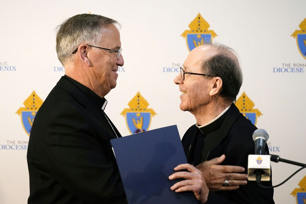 Bishop John Dolan, left, smiles along with retiring Bishop Thomas Olmsted as Dolan is introduced at a news conference after being named the new bishop for the Roman Catholic Diocese of Phoenix Friday, June 10, 2022, in Phoenix. (AP Photo/Ross D. Franklin)