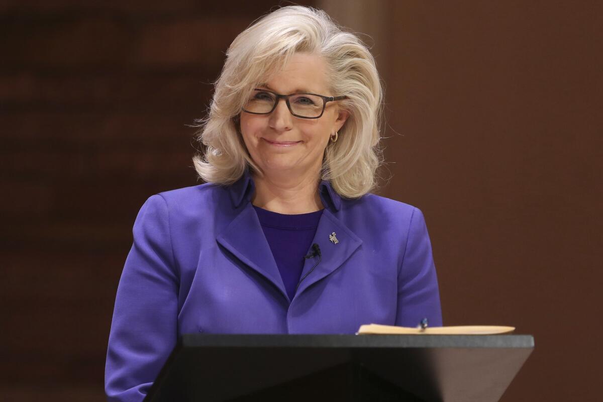 Liz Cheney smiles as she stands at a podium.