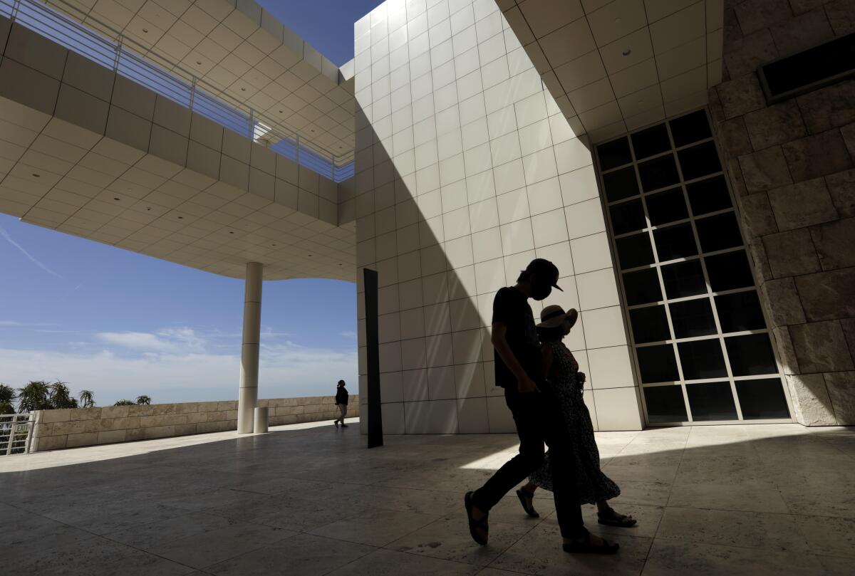 Silhouettes of visitors walking in front of the white tiled buildings of the Getty Center