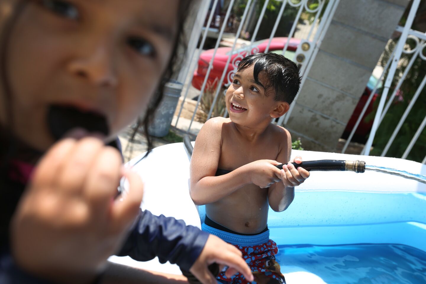 Jocelyn Caravantes, 3, left, and her brother Dean, 6, play in their Boyle Heights pool on a hot afternoon while their mother, Evelyn, watches from a chair in the shade.