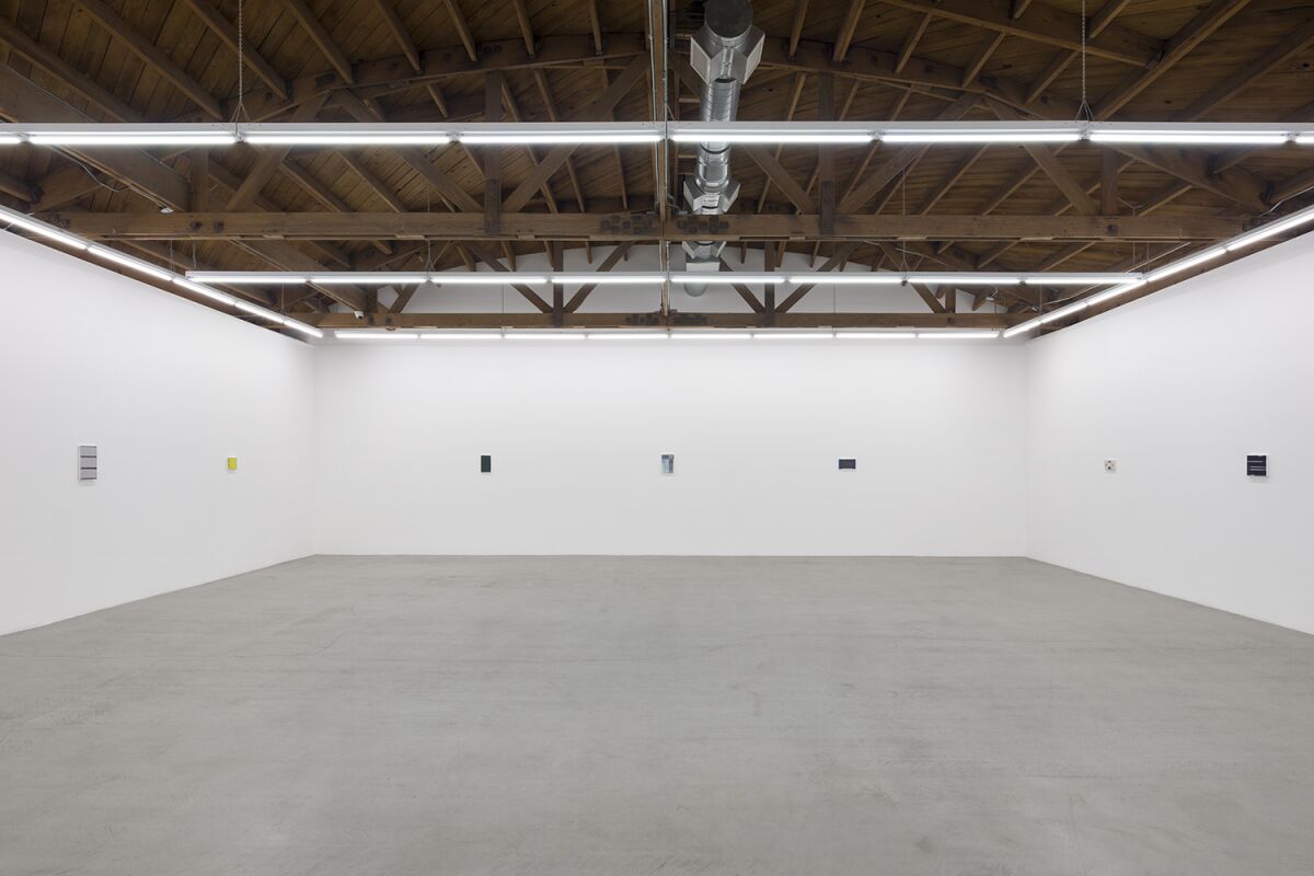 An austere empty room with paintings spaced out on the walls 