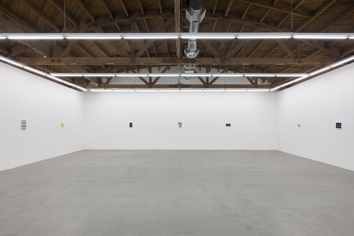 An austere empty room with paintings spaced out on the walls