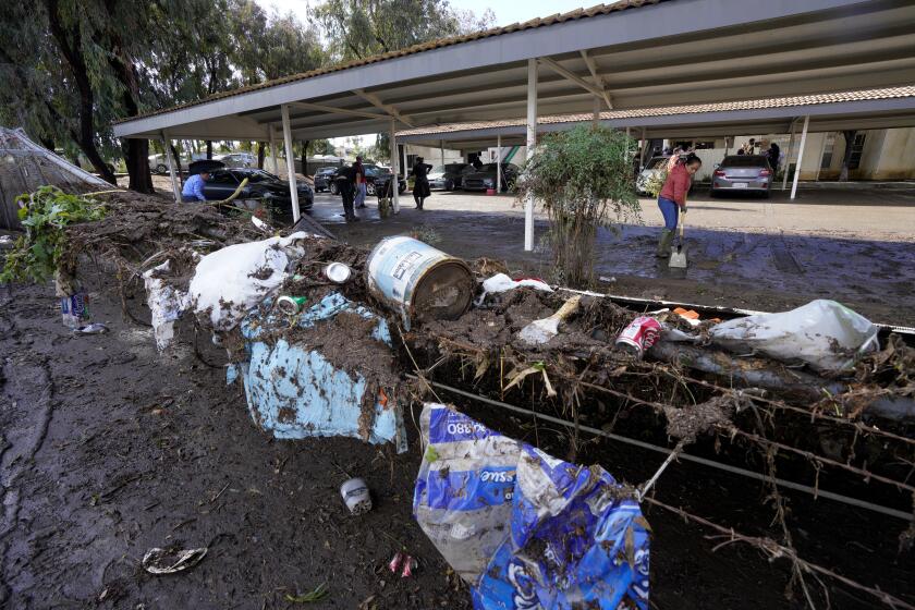 National City CA - January 23: On Tuesday, Jan. 23, 2024 in National City, workers remove mud and debris from the parking lot next to the Happy Hollow Mobile Home Park in National City CA. (Nelvin C. Cepeda / The San Diego Union-Tribune)