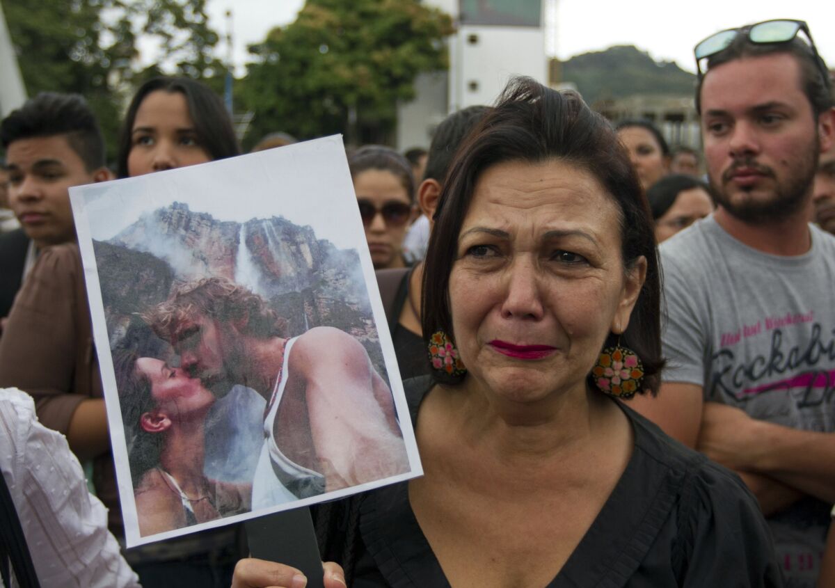 A woman in Caracas, Venezuela, holds up a picture of slain former Miss Venezuela Monica Spear and her ex-husband, Henry Thomas Berry, during a protest against violence.