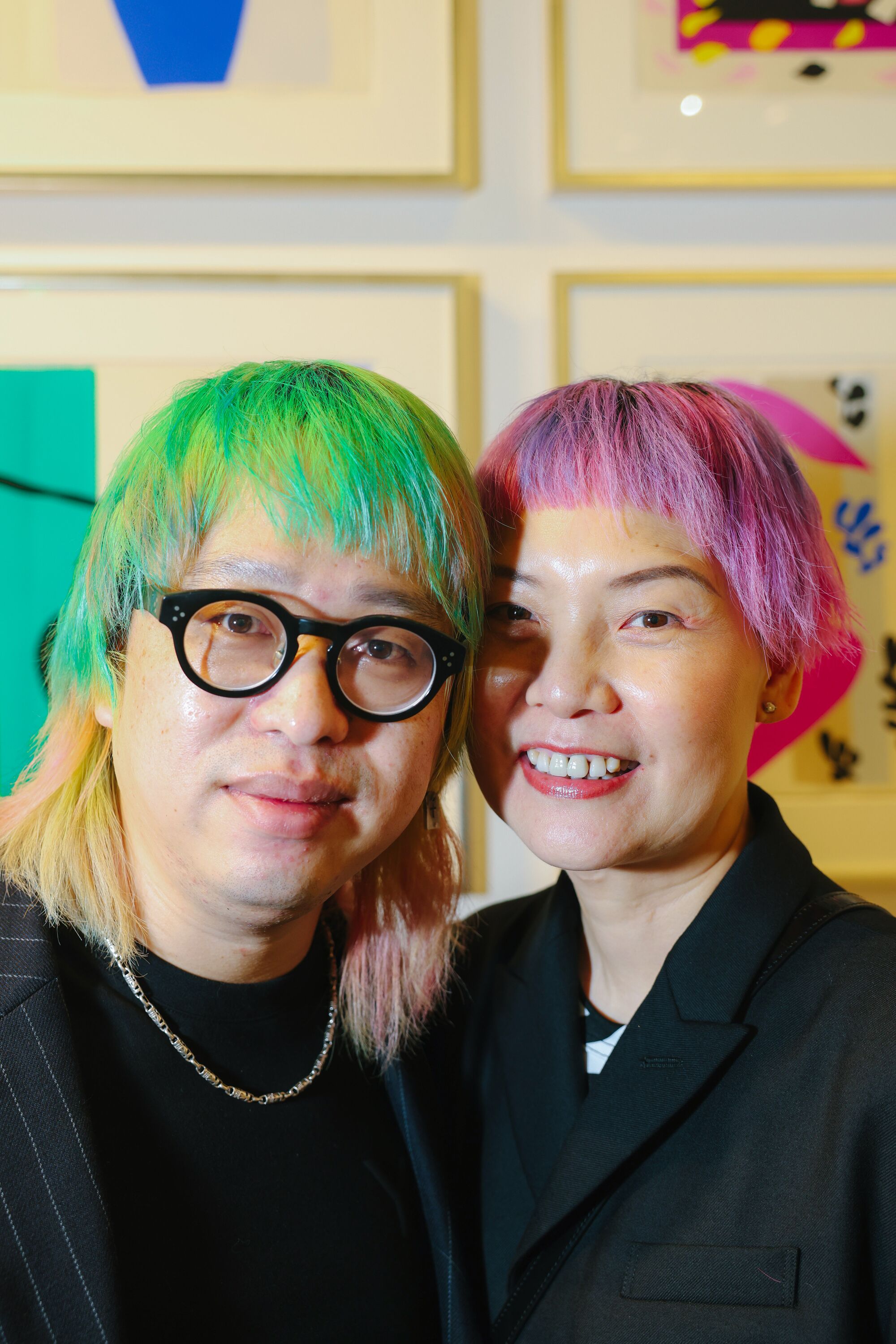 Two people with dyed hair, (green, left, and pink) pose for a photo.