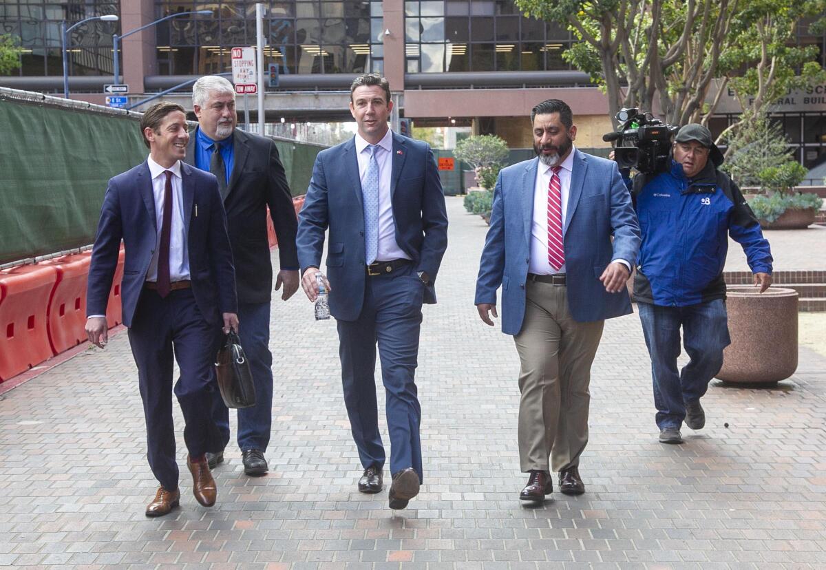Former US Representative Duncan Hunter, center, walks towards Broadway after leaving through the back door of the Federal courthouse in San Diego, CA on March 17th after being sentenced to 11 months in Federal Prison after pleading guilty to a single count related to campaign fraud.