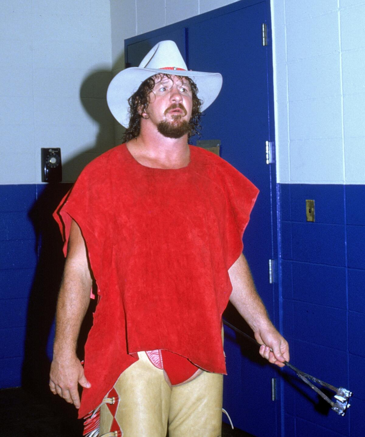 Wrestler Terry Funk wears a cowboy hat and looks down a hallway