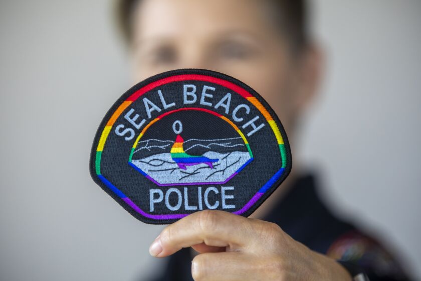 SEAL BEACH, CA - JUNE 28: Portrait of Seal Beach Police Officer Erin Enos holding a rainbow patch on Monday, June 28, 2021 in Seal Beach, CA. Seal Beach, Officer Erin Enos, who is lesbian, pitched the rainbow patch idea to Police Chief Philip Gonshak a few months ago. It was immediately approved and ready to be worn June 1st, which is Pride month. The Seal Beach Police Officers Assn. funded the patches and are available for purchase for $10. Proceeds from the patches will go toward The Trevor Project. The city of Seal Beach also held its first Pride march this year, too. (Francine Orr / Los Angeles Times)