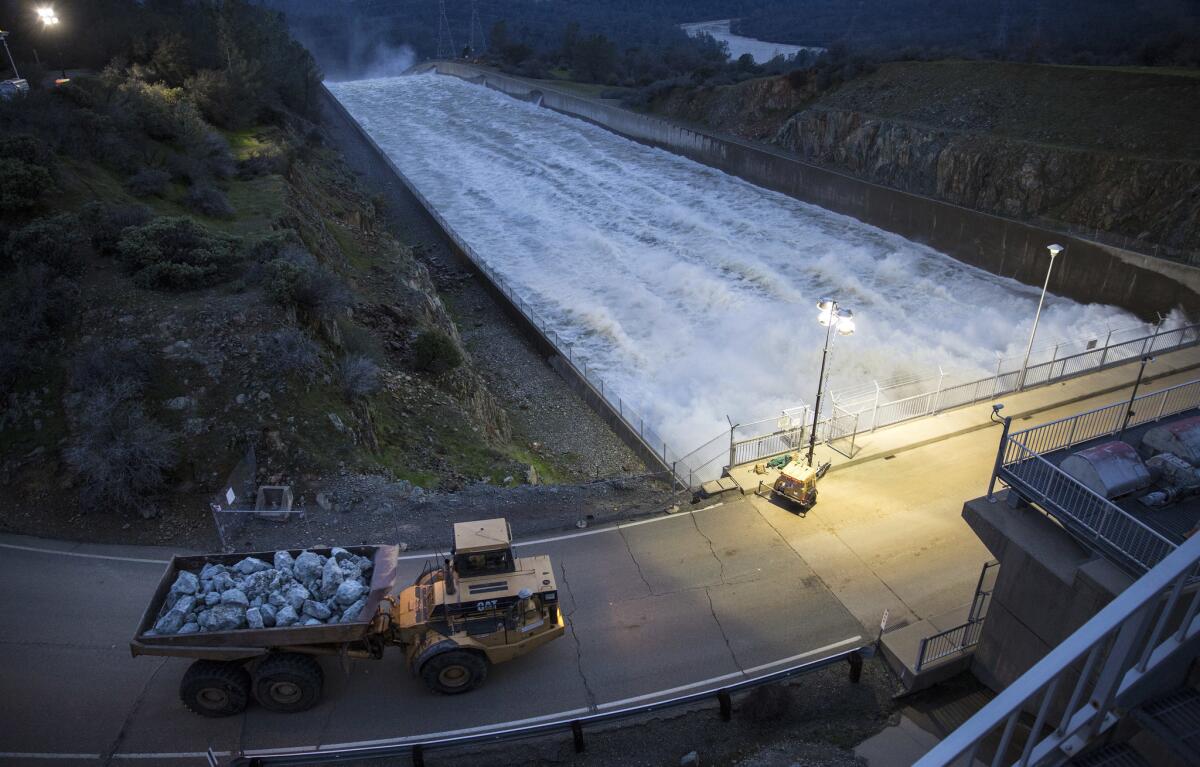 A dump truck crosses the primary spillway to deliver boulders to the damaged emergency spillway at Lake Oroville on Monday evening.