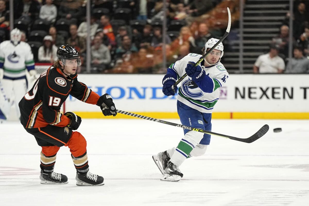 Vancouver Canucks defenseman Quinn Hughes, passes the puck while under pressure from Ducks right wing Troy Terry.