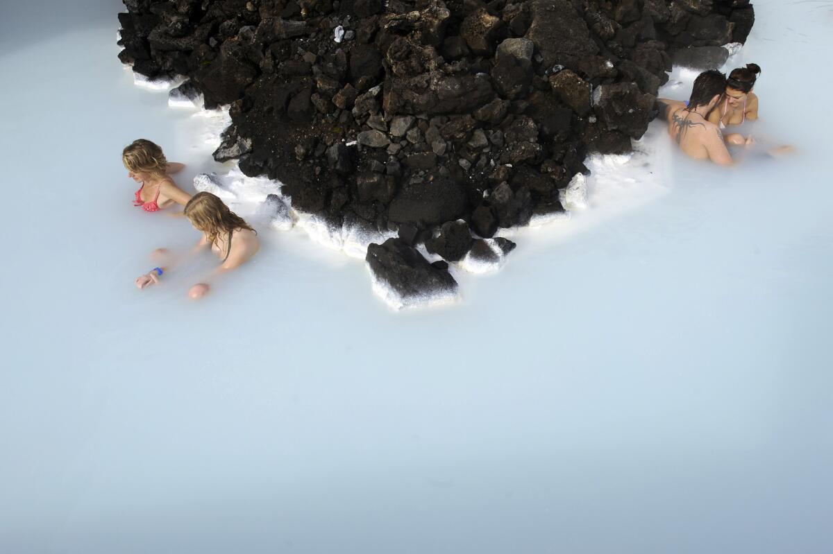 Tourists sit in the Blue Lagoon outside Reykjavik. The Blue Lagoon's blue and green waters come from natural hot water springs flowing through a lava field.