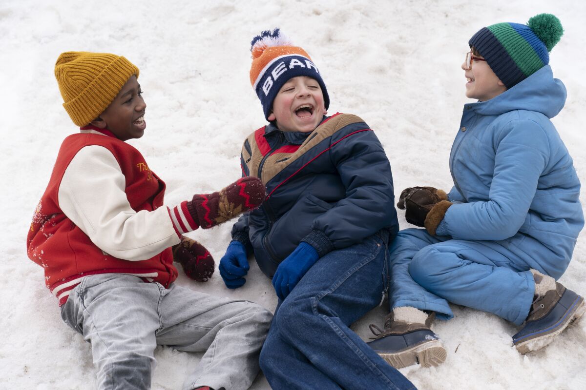 Three kids laughing while lying in the snow 