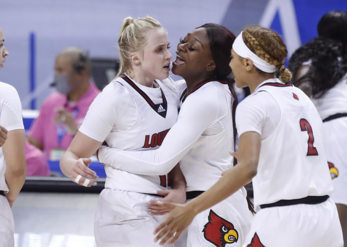Louisville's Dana Evans, center, celebrates with Hailey Van Lith, left, and Ahlana Smith, right, during the second half of Louisville's 65-53 victory over Wake Forest in the quarterfinals of the Atlantic Coast Conference NCAA women's college basketball game in Greensboro, N.C., Friday, March 5, 2021. (Ethan Hyman/The News & Observer via AP)