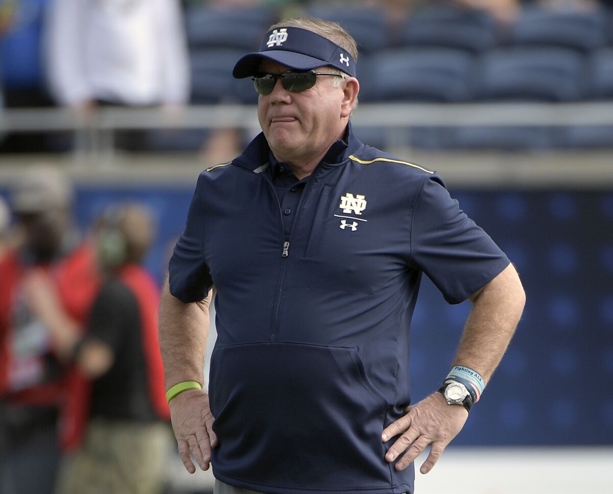 Notre Dame coach Brian Kelly watches players warming up before a game.