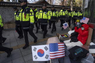 Police officers file past Yoon supporters in Seoul on Thursday.