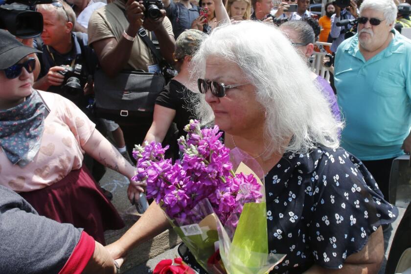 Susan Bro, center, mother of Heather Heyer who was killed during last year's Unite the Right rally, and her husband, Kim, right, speak to supporters after laying flowers at the spot her daughter was killed in Charlottesville, Va., Sunday, Aug. 12, 2018. Bro said there's still "so much healing to do." She said the city and the country have a "huge racial problem" and that if it's not fixed, "we'll be right back here in no time." (AP Photo/Steve Helber)