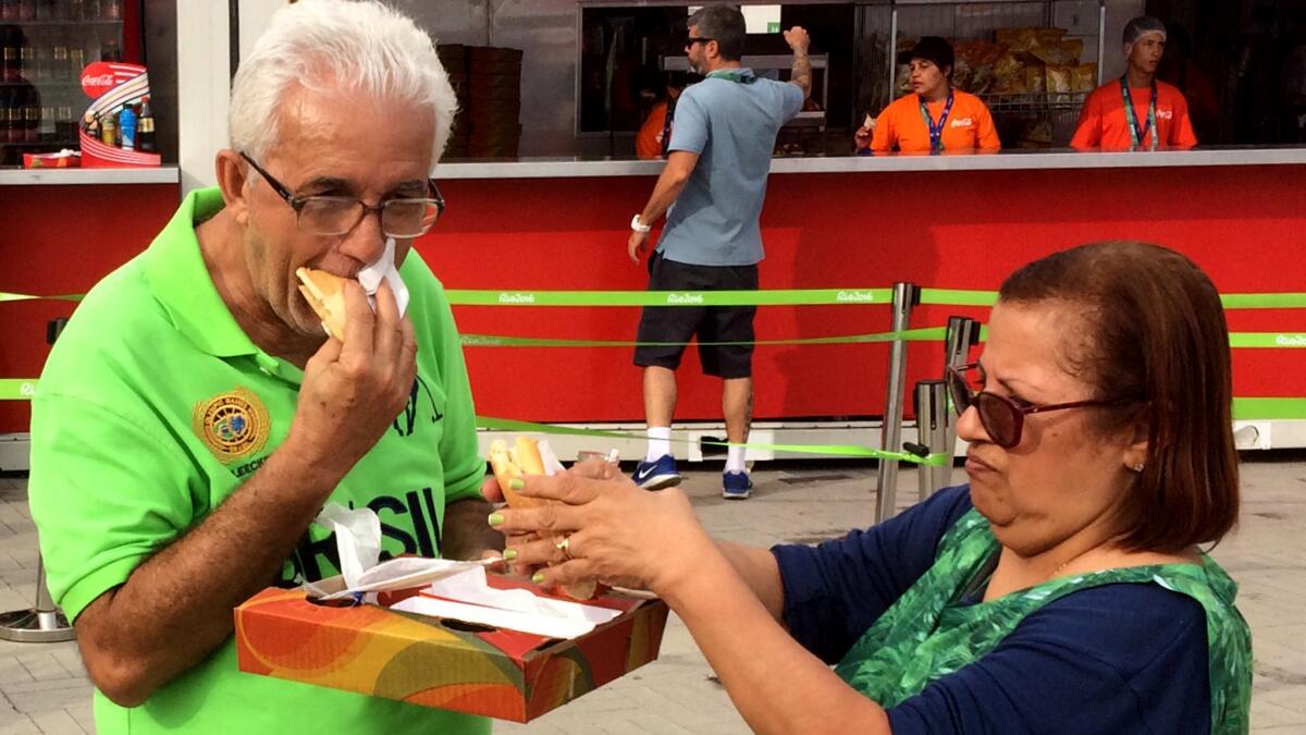 Two Brazilians enjoy sandwiches at the Olympic Park, where cheeseburgers, hot dogs, pizza and corndogs are among the selections.