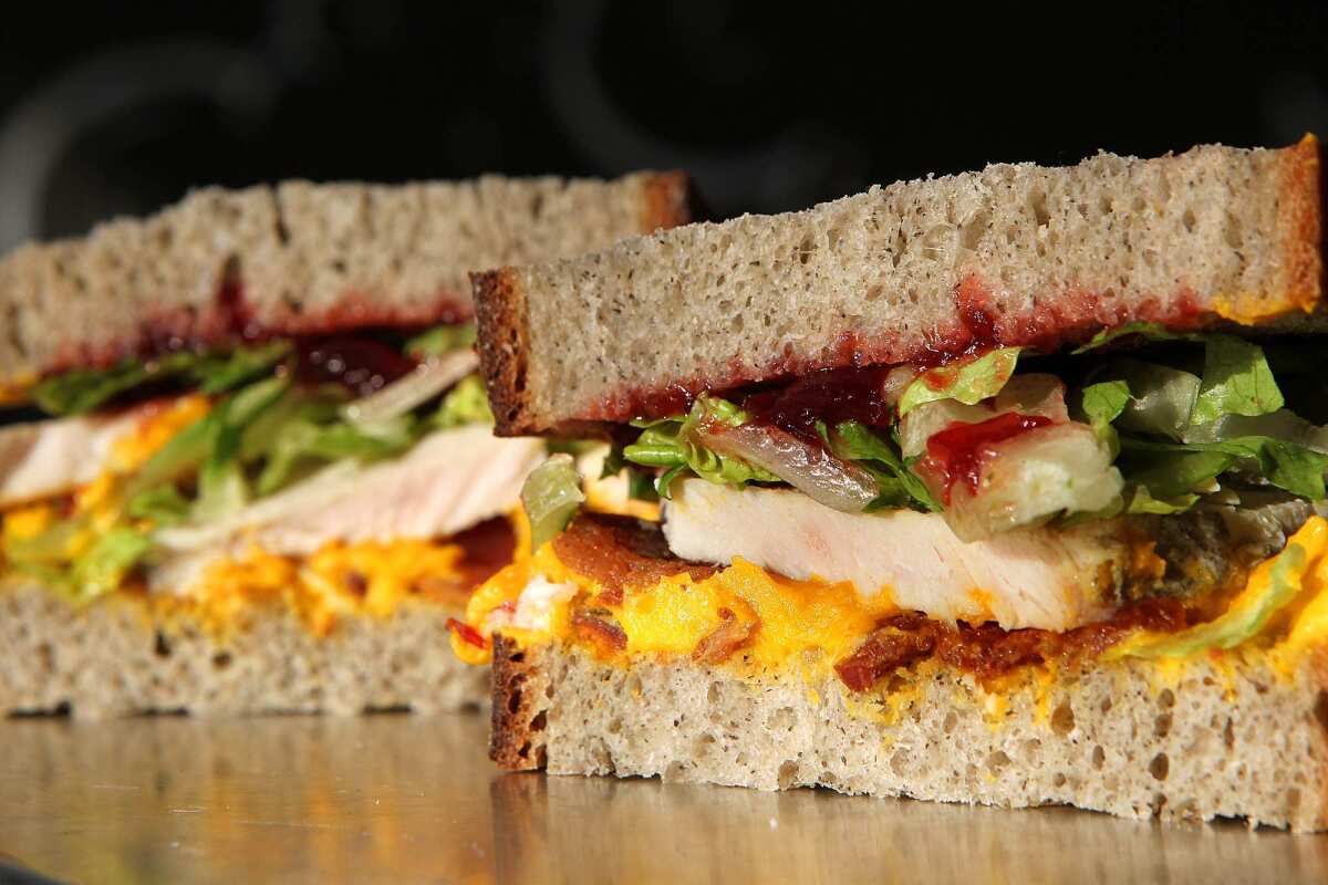 A turkey sandwich made with buckwheat bread, kabosha squash whipped with creme fraiche, applewood smoked bacon, hot carved turkey, romaine, and cranberry chutney prepared at Mendocino Farms in West Hollywood. Recipe.