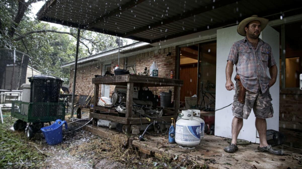 Wyatt Sebesta, 34, carries a revolver as he finishes moving most of the contents of his home to higher ground as the Brazos River surges nearby.